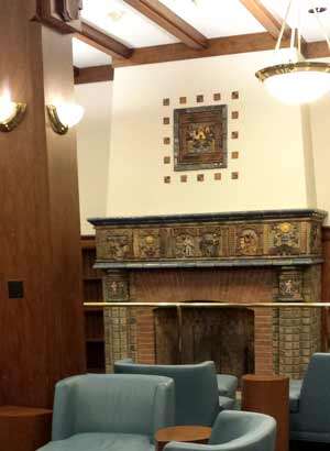 Photograph of the fireplace with various tiles lined on the mantle with the large, solo El Dorado tile on the chimney breast.