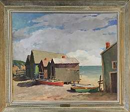 Row of gable roofed cottages with canoes next to them by the beach under a blue sky with large fluffy clouds.